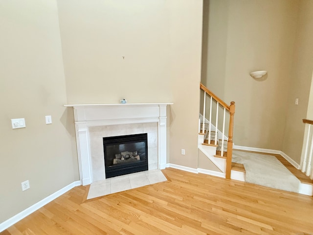 253 Summerfield Gdns Unit 253, Shelton, CT 06484 - unfurnished living room with wood finished floors, a tiled fireplace, stairs, and baseboards