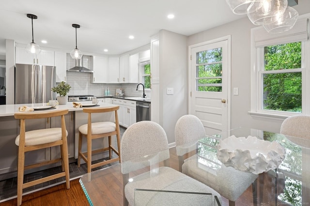 128 W Ave, Darien, CT 06820 - kitchen featuring appliances with stainless steel finishes, wall chimney exhaust hood, backsplash, dark wood-style flooring, and white cabinets