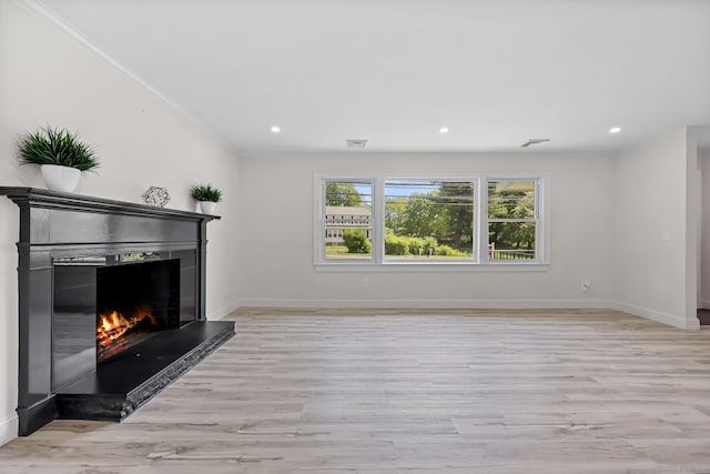 unfurnished living room featuring a lit fireplace, light wood-style floors, baseboards, crown molding, and recessed lighting