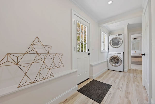 laundry area featuring stacked washer / drying machine, wood finished floors, ornamental molding, and baseboards