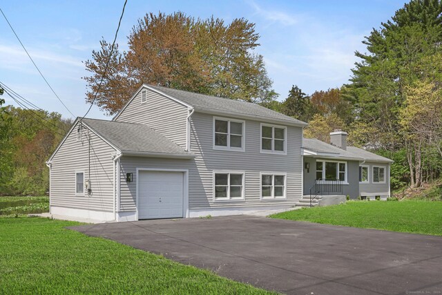 tri-level home featuring an attached garage, driveway, a front lawn, and a chimney