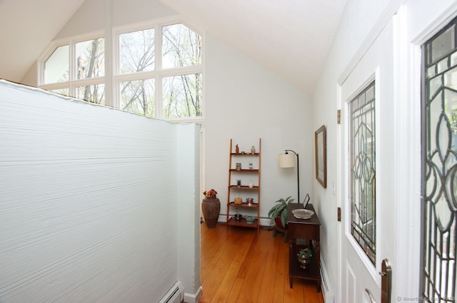 hall with light wood-style floors, baseboard heating, and vaulted ceiling