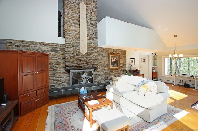 living room with high vaulted ceiling, a fireplace, hardwood / wood-style floors, and a notable chandelier