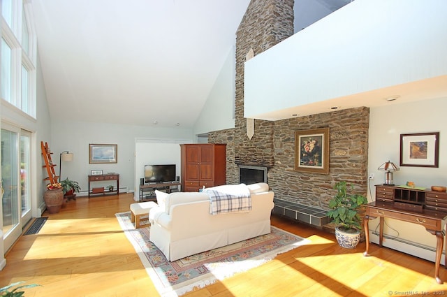 living room featuring a stone fireplace, a baseboard heating unit, wood finished floors, and high vaulted ceiling