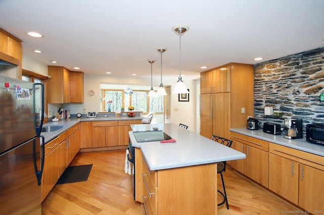 kitchen with a breakfast bar area, a kitchen island, black appliances, light wood finished floors, and recessed lighting