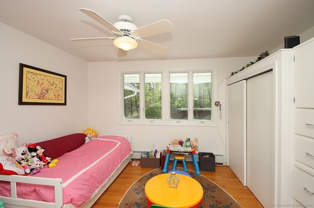 bedroom featuring light wood-style floors, a ceiling fan, and a baseboard radiator