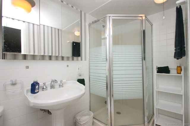 bathroom featuring tile walls, a shower stall, and tasteful backsplash