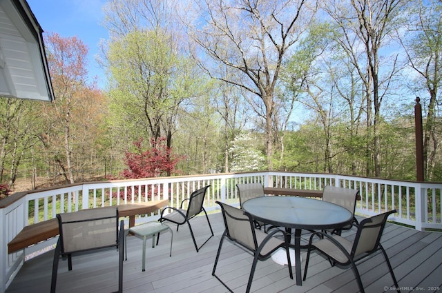 wooden terrace with a forest view and outdoor dining space