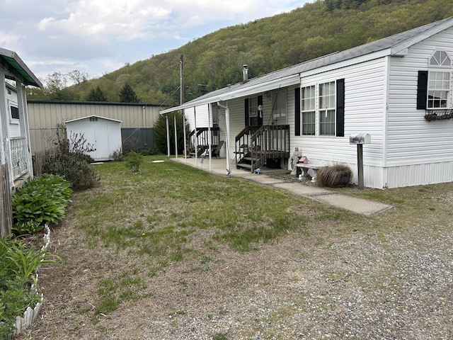 exterior space with a storage shed, a yard, an outdoor structure, and a view of trees