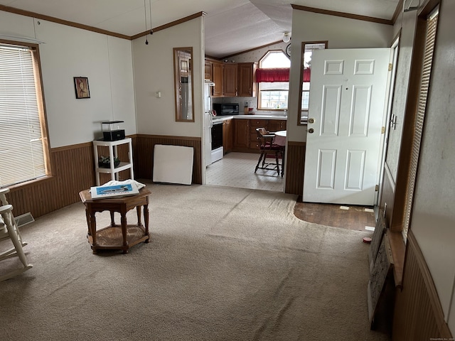 interior space featuring crown molding, lofted ceiling, light carpet, light countertops, and a wainscoted wall