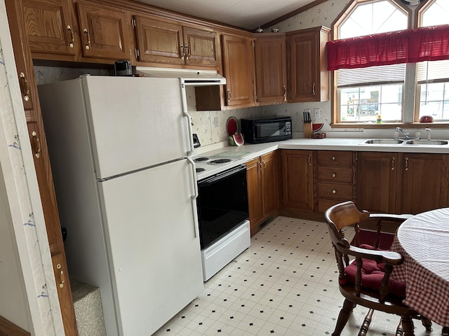kitchen featuring vaulted ceiling, a sink, light countertops, light floors, and white appliances