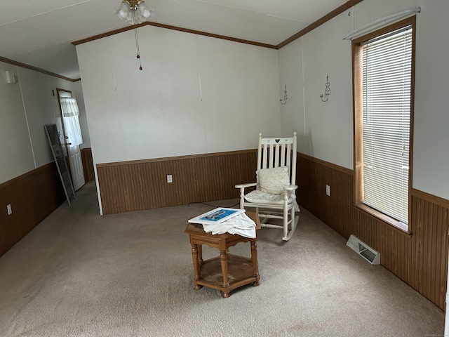 sitting room with visible vents, wainscoting, crown molding, and wooden walls