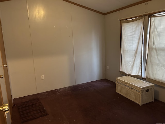 empty room featuring crown molding and carpet floors
