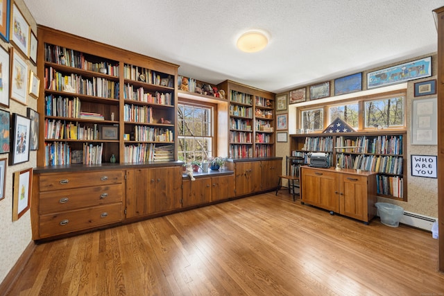 7 Partridge Ln, Burlington, CT 06013 - office area with wallpapered walls, light wood-style flooring, bookshelves, a baseboard heating unit, and a textured ceiling