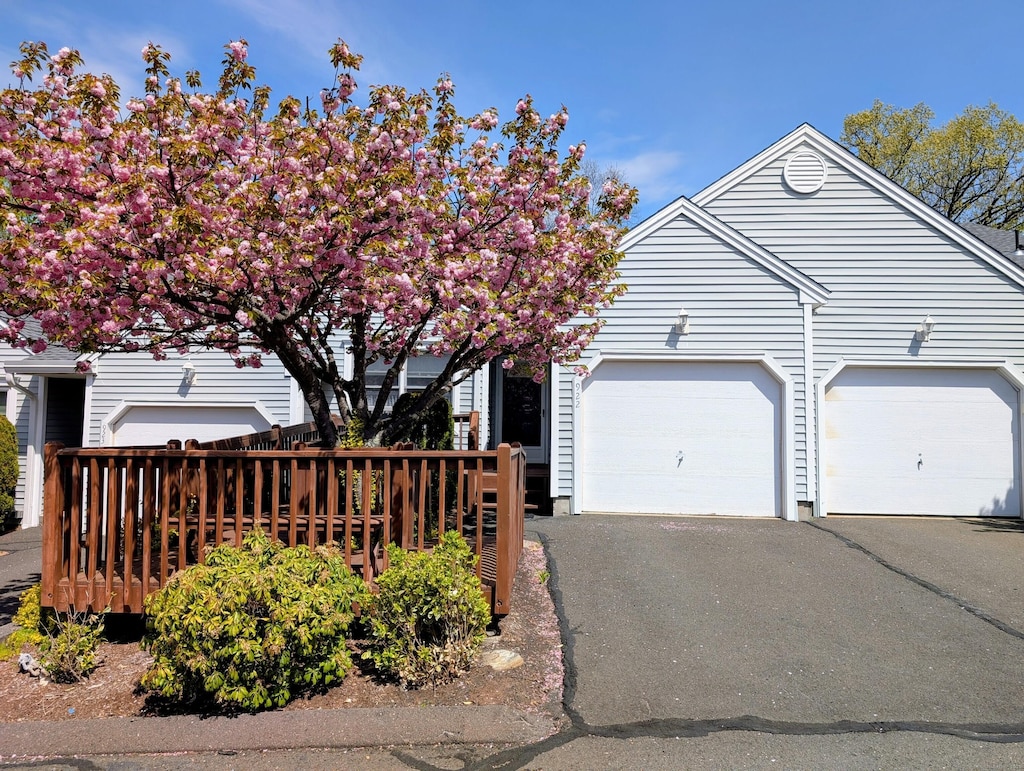 view of property hidden behind natural elements featuring an attached garage and driveway