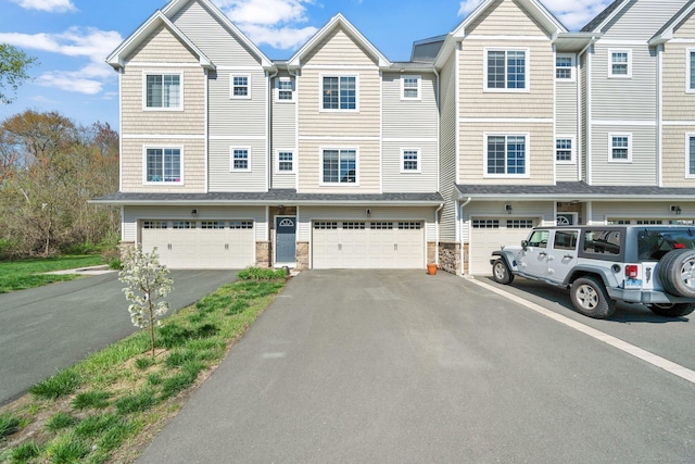 multi unit property featuring driveway, a garage, and stone siding