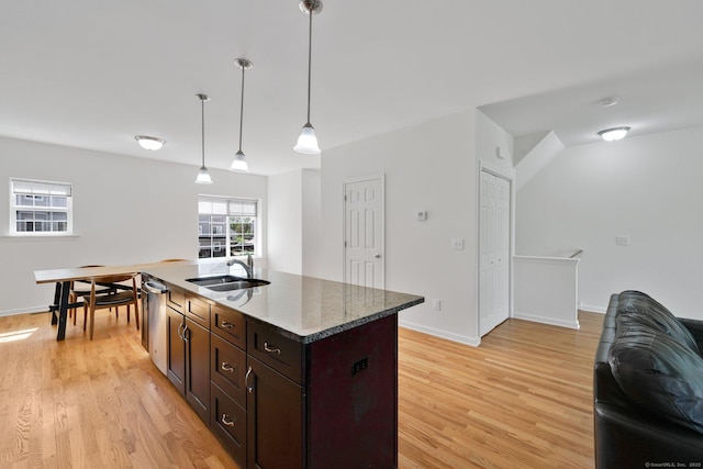 kitchen with light wood finished floors, a sink, pendant lighting, and dark brown cabinets