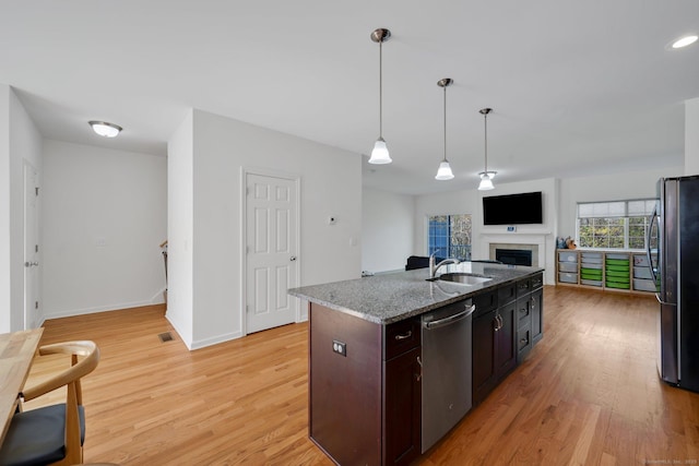 kitchen with stainless steel appliances, light wood-type flooring, open floor plan, hanging light fixtures, and a fireplace