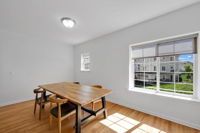 dining space featuring baseboards and light wood finished floors