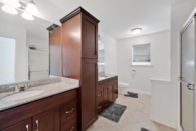 full bathroom with a shower stall, vanity, baseboards, toilet, and tile patterned floors
