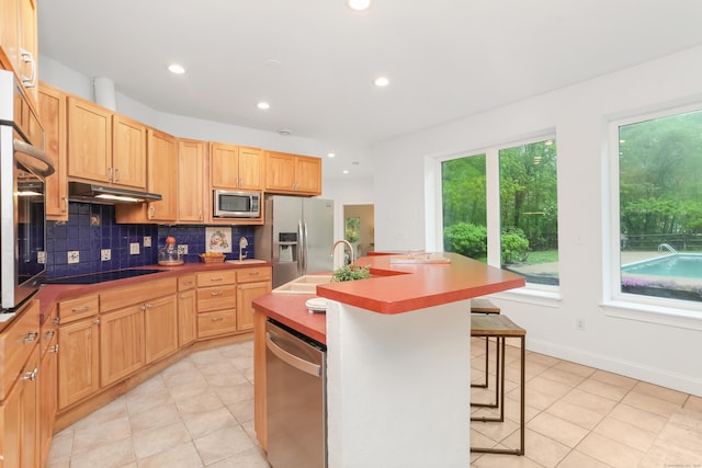 28 Drewbarrie Ln, Easton, CT 06612 - kitchen with under cabinet range hood, light tile patterned flooring, decorative backsplash, a center island with sink, and appliances with stainless steel finishes