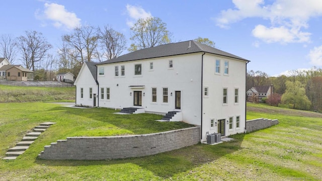 rear view of house with a yard, central AC, entry steps, and stucco siding