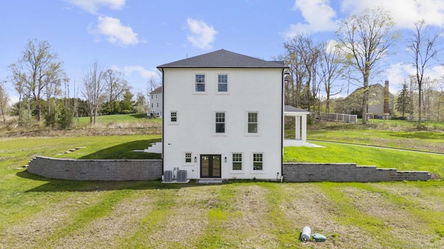 rear view of house with french doors, stucco siding, a yard, and central AC