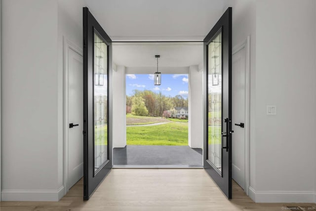 doorway to outside featuring baseboards and wood finished floors