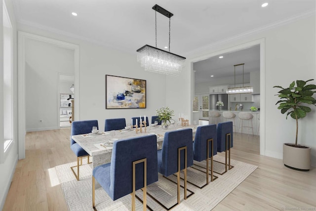 dining space featuring light wood-style floors, ornamental molding, a notable chandelier, and recessed lighting