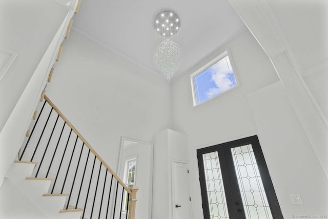 entrance foyer featuring stairs, a chandelier, french doors, and a towering ceiling