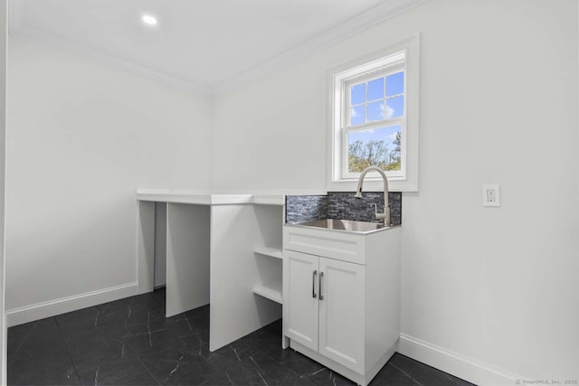 laundry area featuring baseboards, ornamental molding, and a sink