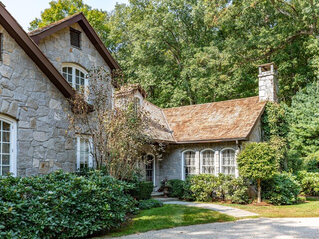 view of front of property featuring stone siding and a chimney