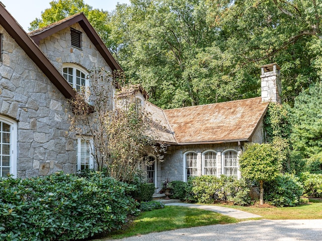 view of front of house with stone siding and a chimney