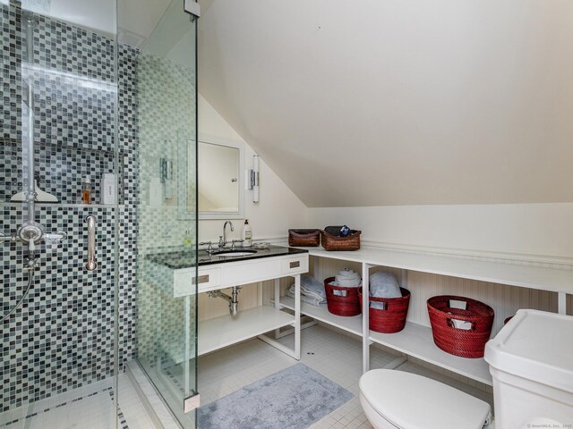 bathroom with toilet, a shower stall, lofted ceiling, vanity, and tile patterned flooring