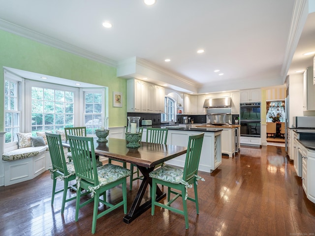 dining room featuring ornamental molding, dark wood-type flooring, recessed lighting, and a wainscoted wall