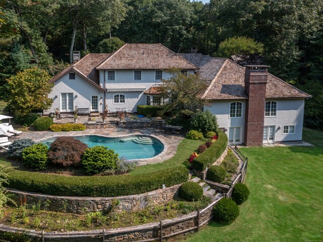 outdoor pool with french doors, a lawn, and a patio area