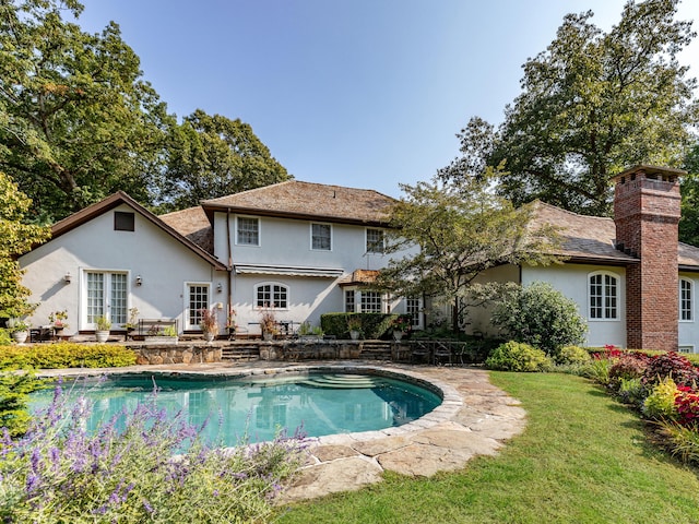 outdoor pool with a patio and a lawn