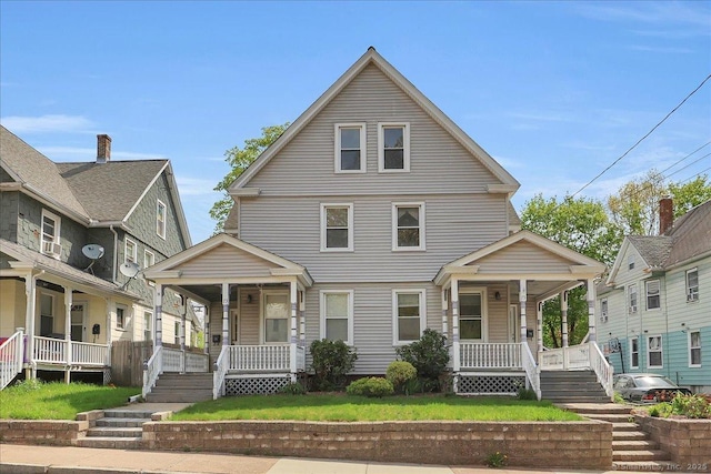 american foursquare style home featuring covered porch and a front yard