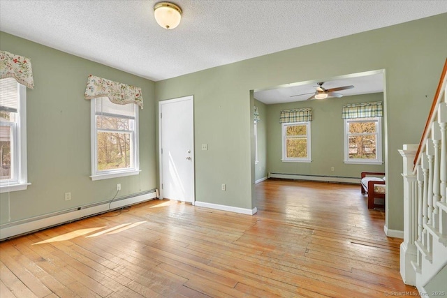 unfurnished room with ceiling fan, a baseboard heating unit, and plenty of natural light