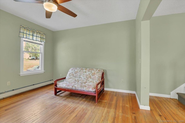 living area with baseboards, ceiling fan, stairway, hardwood / wood-style flooring, and a baseboard radiator