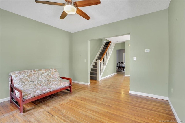 sitting room featuring light wood-type flooring, a ceiling fan, and stairway