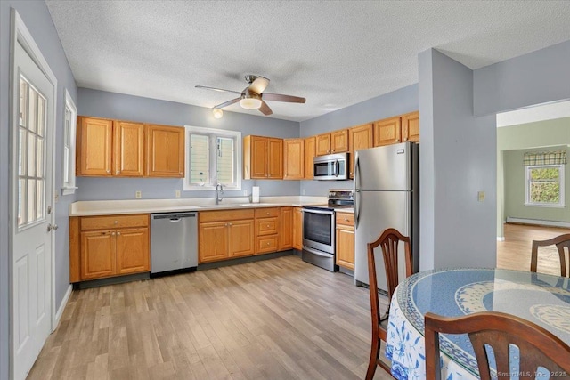 kitchen featuring stainless steel appliances, a baseboard heating unit, and light wood-style flooring