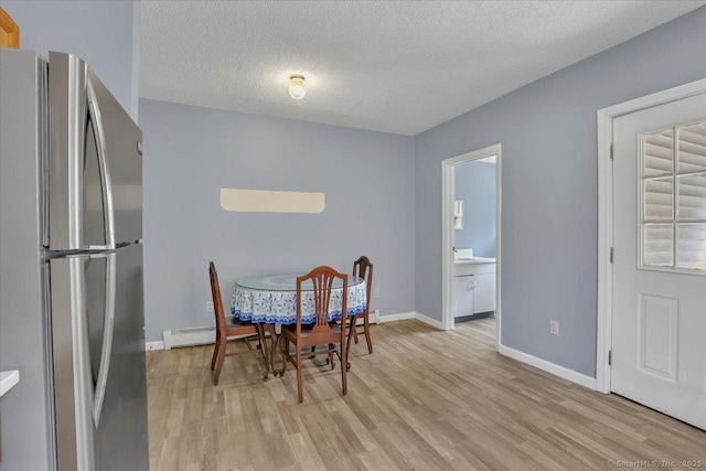 dining space featuring a textured ceiling, baseboards, and light wood-type flooring