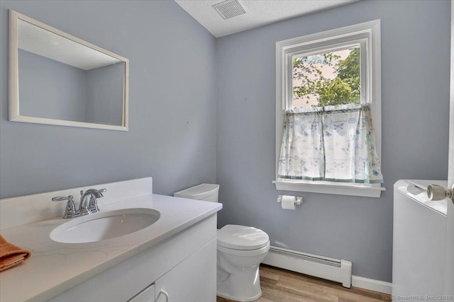 bathroom with visible vents, vanity, wood finished floors, toilet, and a baseboard heating unit