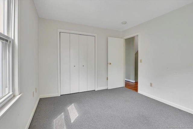 unfurnished bedroom with carpet flooring, baseboards, and a closet