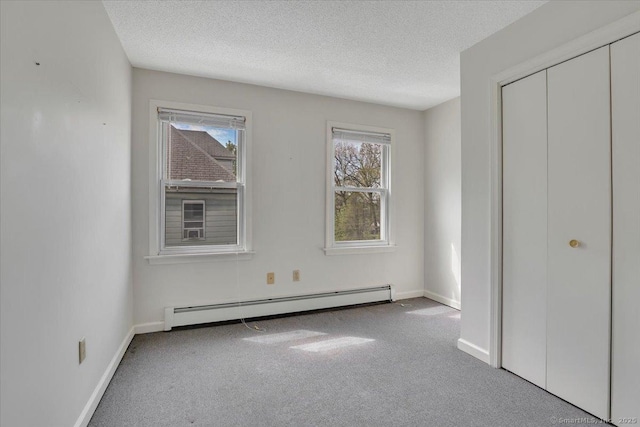 unfurnished bedroom featuring baseboards, a textured ceiling, carpet, and baseboard heating