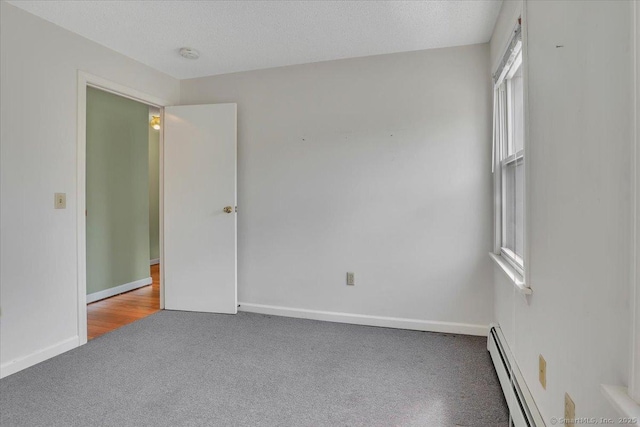 carpeted spare room featuring baseboards, a textured ceiling, and baseboard heating