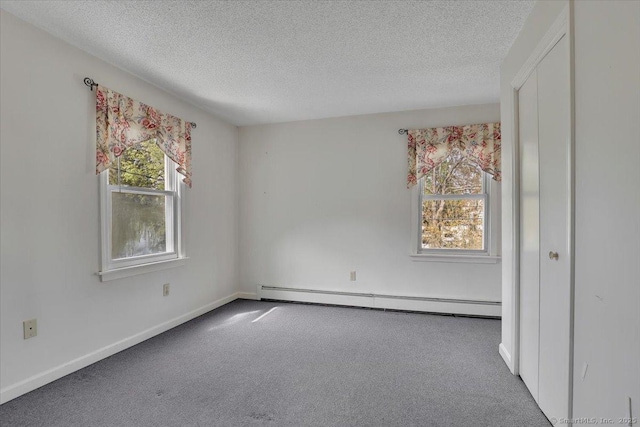 carpeted empty room featuring baseboards, a textured ceiling, and a baseboard heating unit