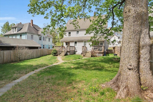back of house featuring a fenced backyard, a wooden deck, and a yard