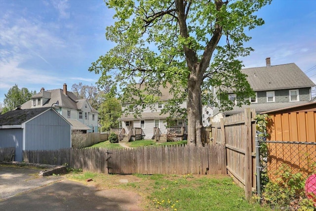 view of yard with a fenced backyard, a gate, a deck, and a storage shed